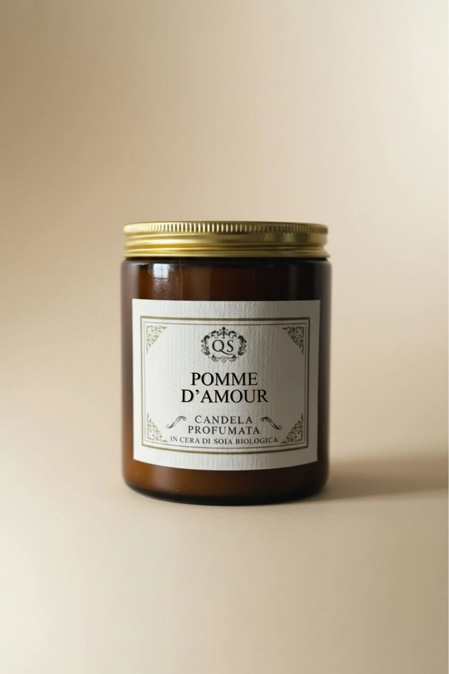 Candela soia Pomme d’Amour in vetro ambrato con etichetta classica su sfondo beige