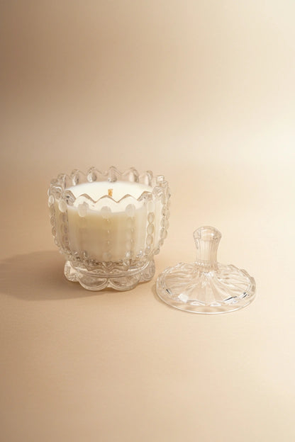 Candela artigianale in cera di soia in contenitore di vetro trasparente con coperchio sfondo beige neutro