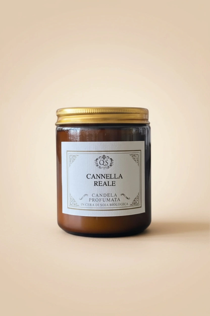 Candela soia Cannella Reale in vetro ambrato con tappo dorato su sfondo beige