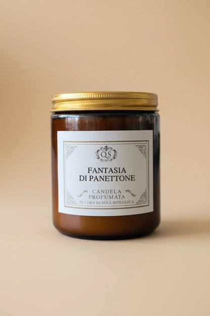 Candela soia Fantasia di Panettone in vetro ambrato con tappo dorato su sfondo beige