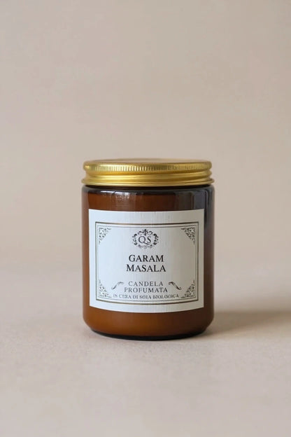 Candela soia Garam Masala in vetro ambrato con tappo dorato su sfondo beige