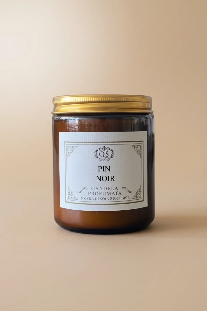 Candela profumata alla soia Pin Noir in vetro ambrato con tappo dorato su sfondo beige